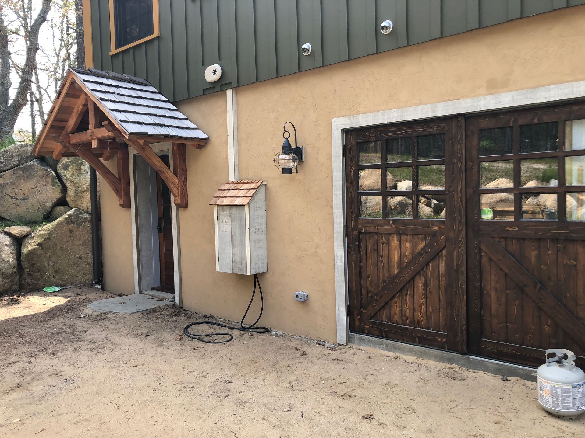 Exterior of building with tan stucco and wooden door, awning, and garage.
