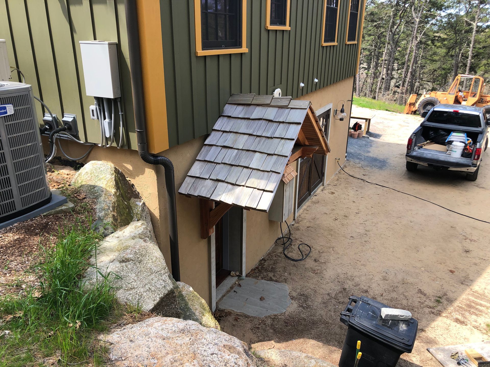 Side of a house with small roof over door, AC unit, and work truck.