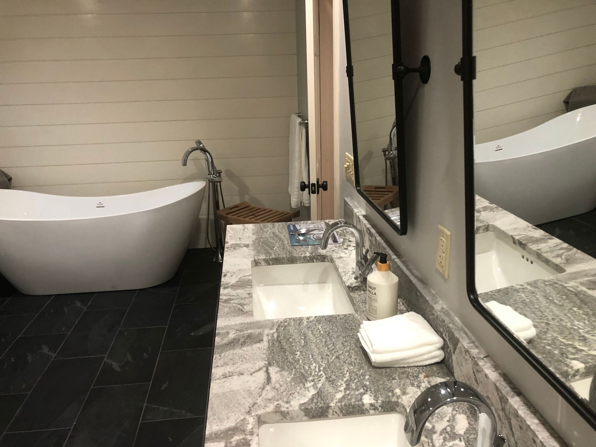 Modern bathroom with a white tub, double sink, and large mirror.