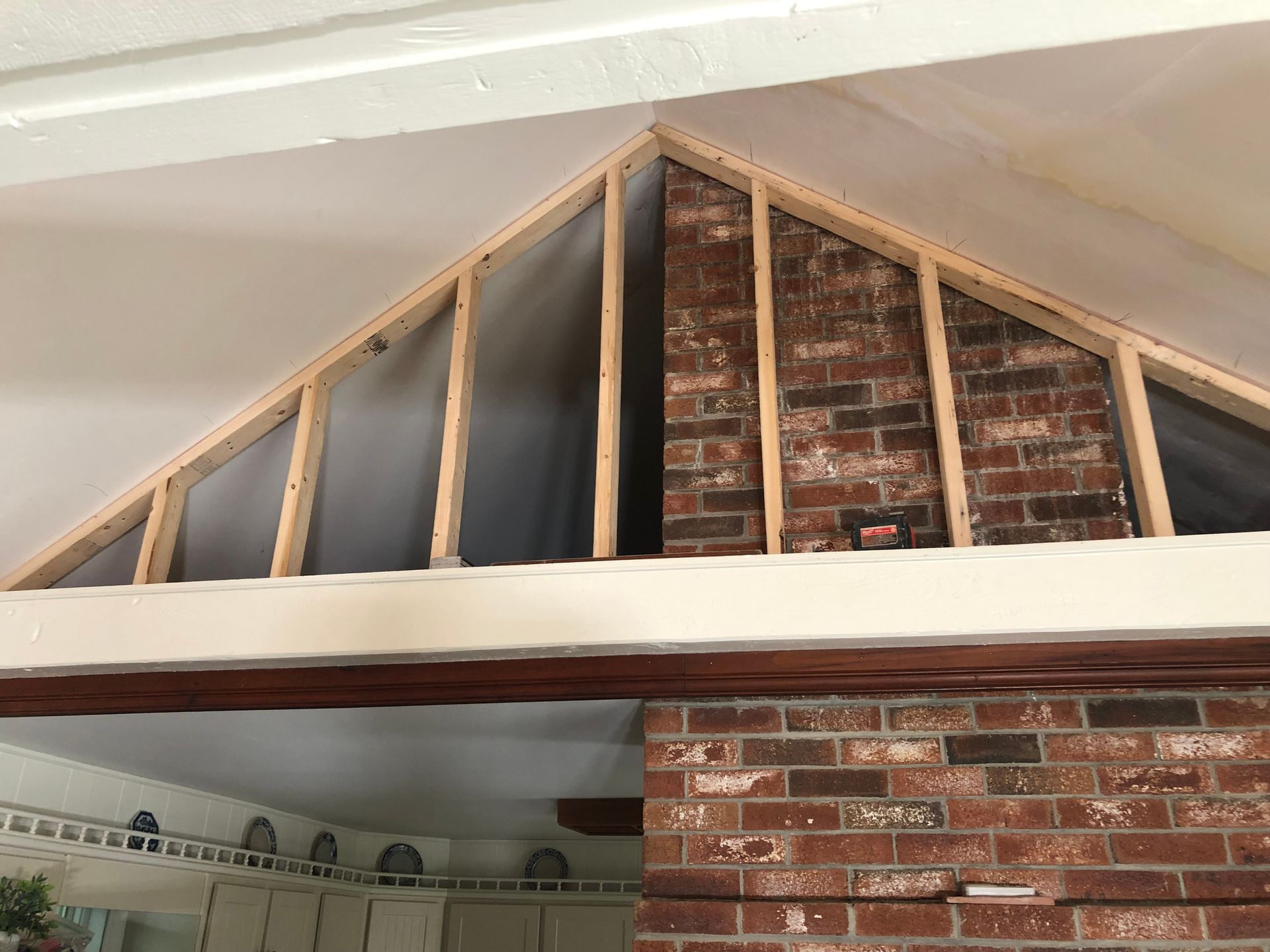 Interior with wooden framing around a brick chimney, under a white ceiling and beam.