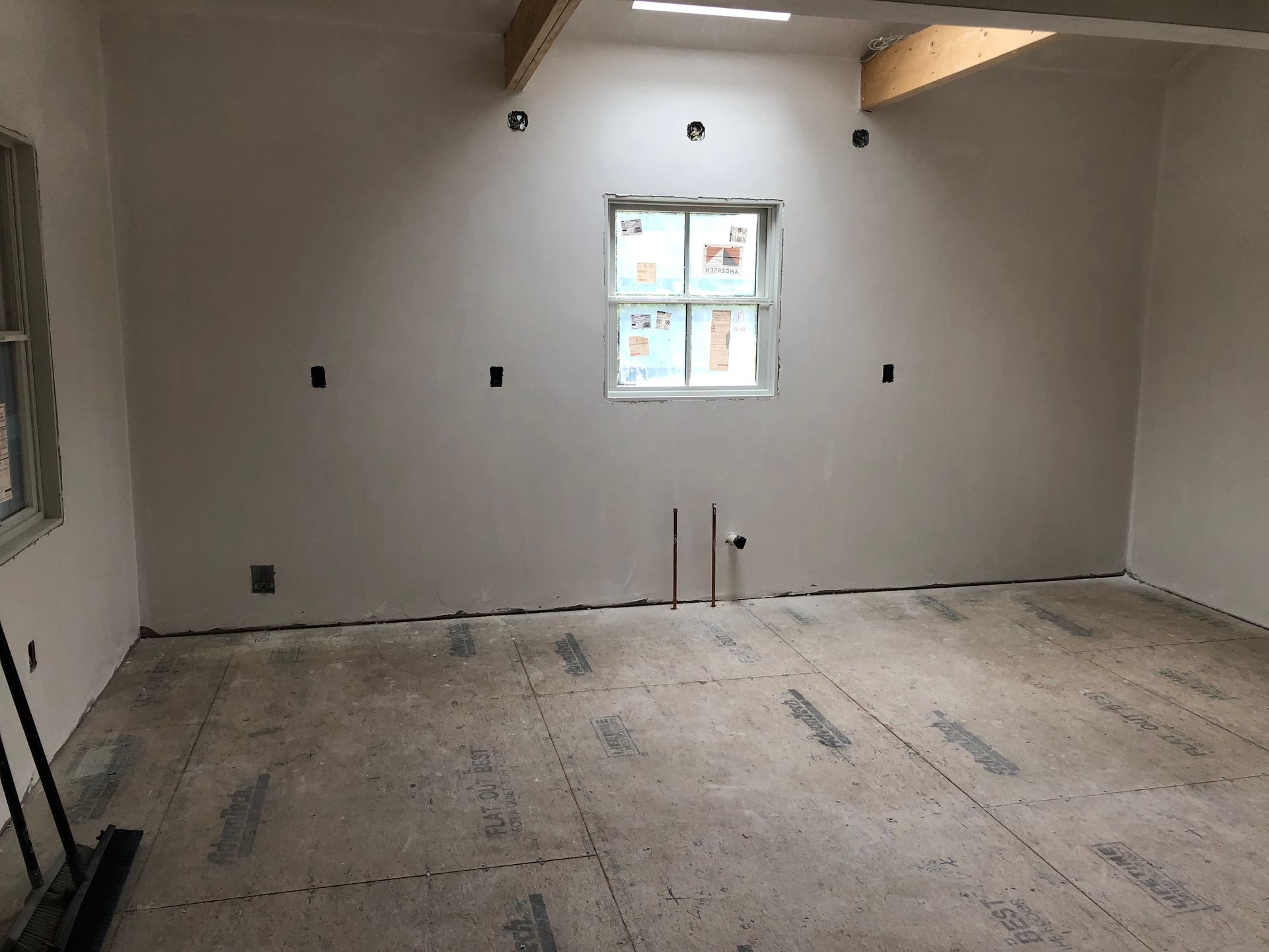 Interior of a room under construction with a window, skylight, and unfinished flooring.