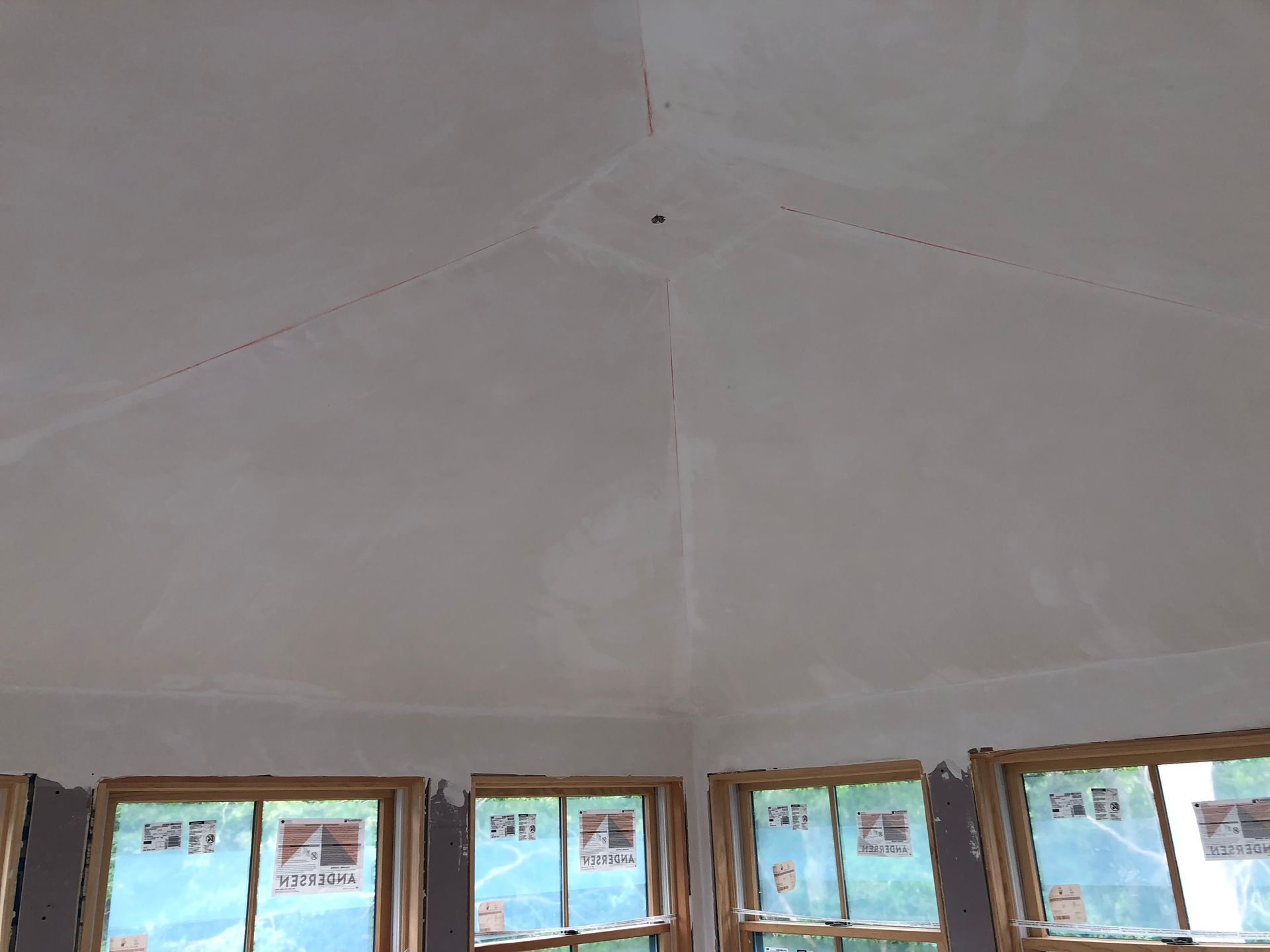 Interior view of a room with a white angled ceiling, windows along the bottom, and unfinished walls.