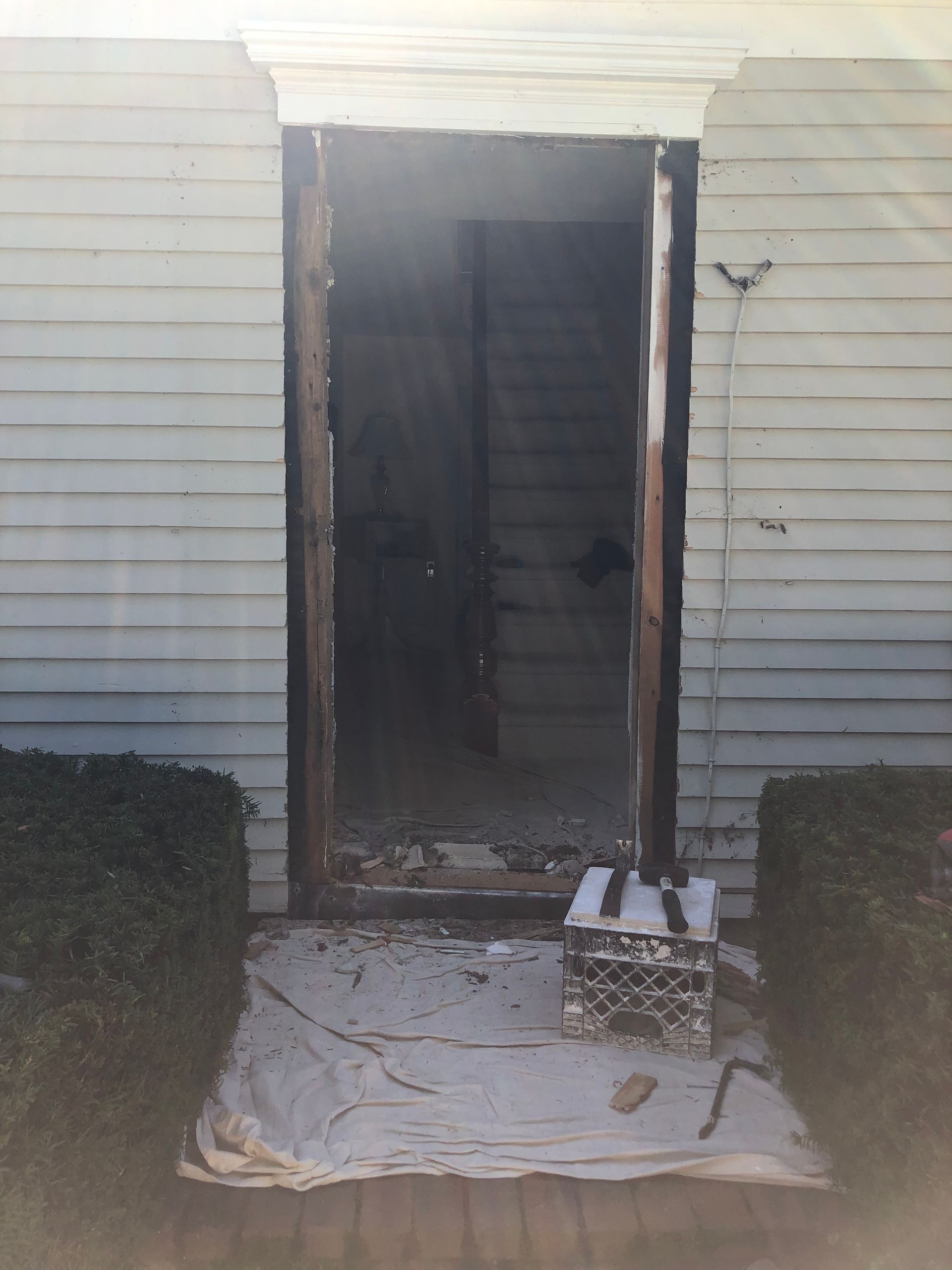 Exterior doorway with wood frame removed, revealing stairs inside.