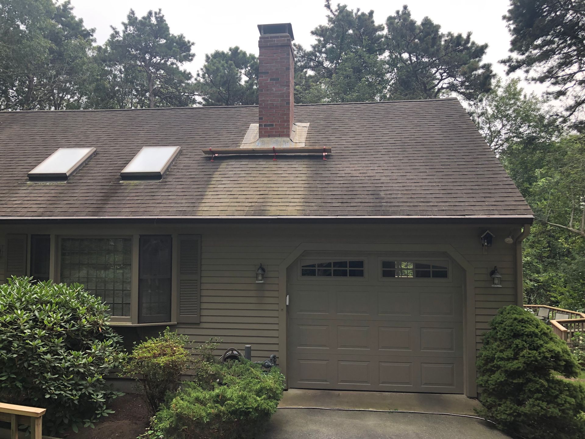 House exterior with a dark roof, three skylights, and a brick chimney.