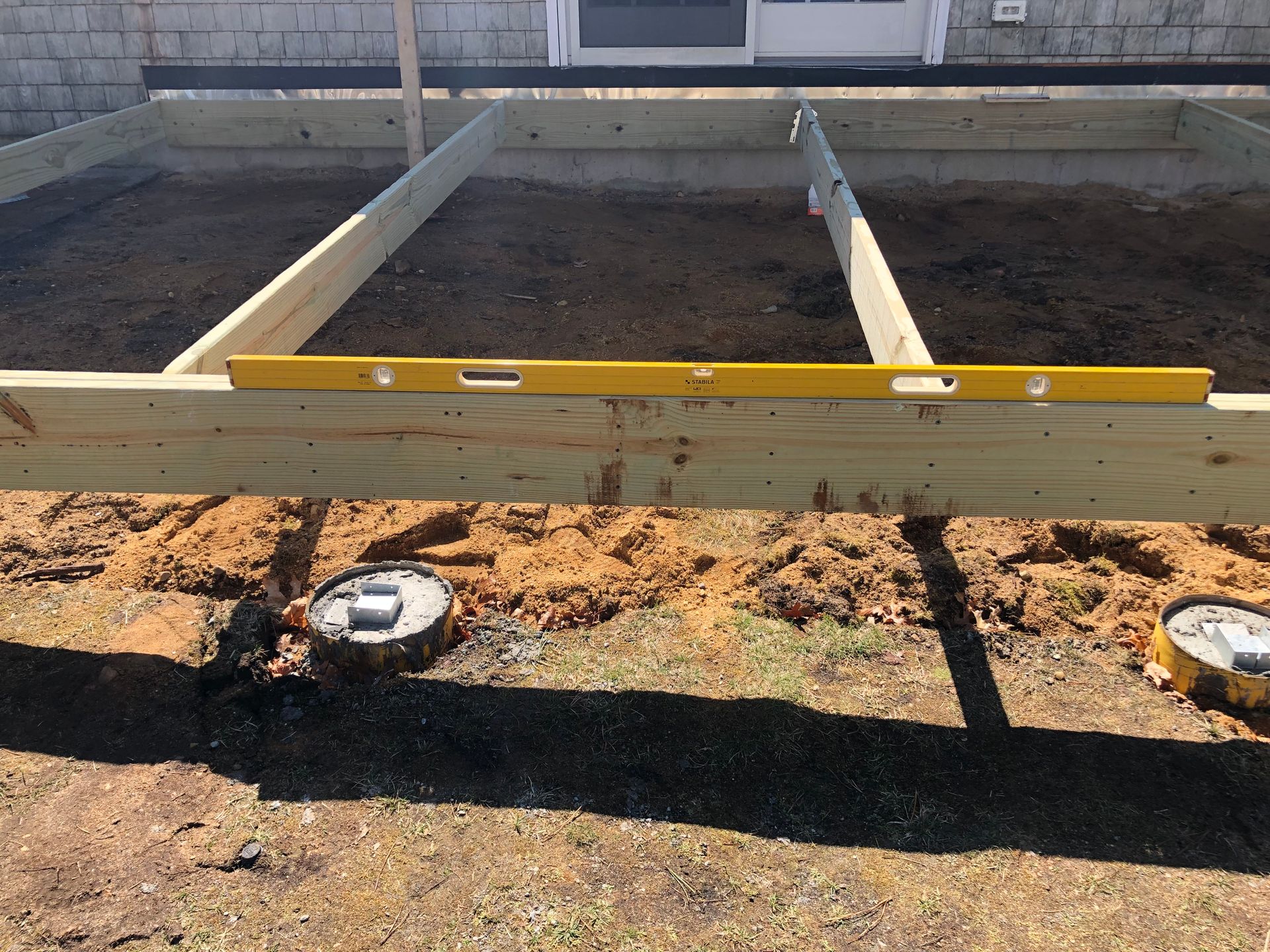 Deck frame under construction, with level, on concrete footings.