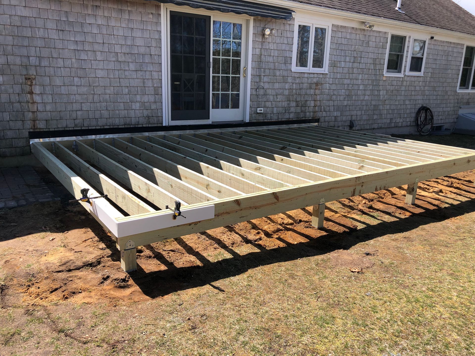 Framed wooden deck under construction; against a weathered brick building.