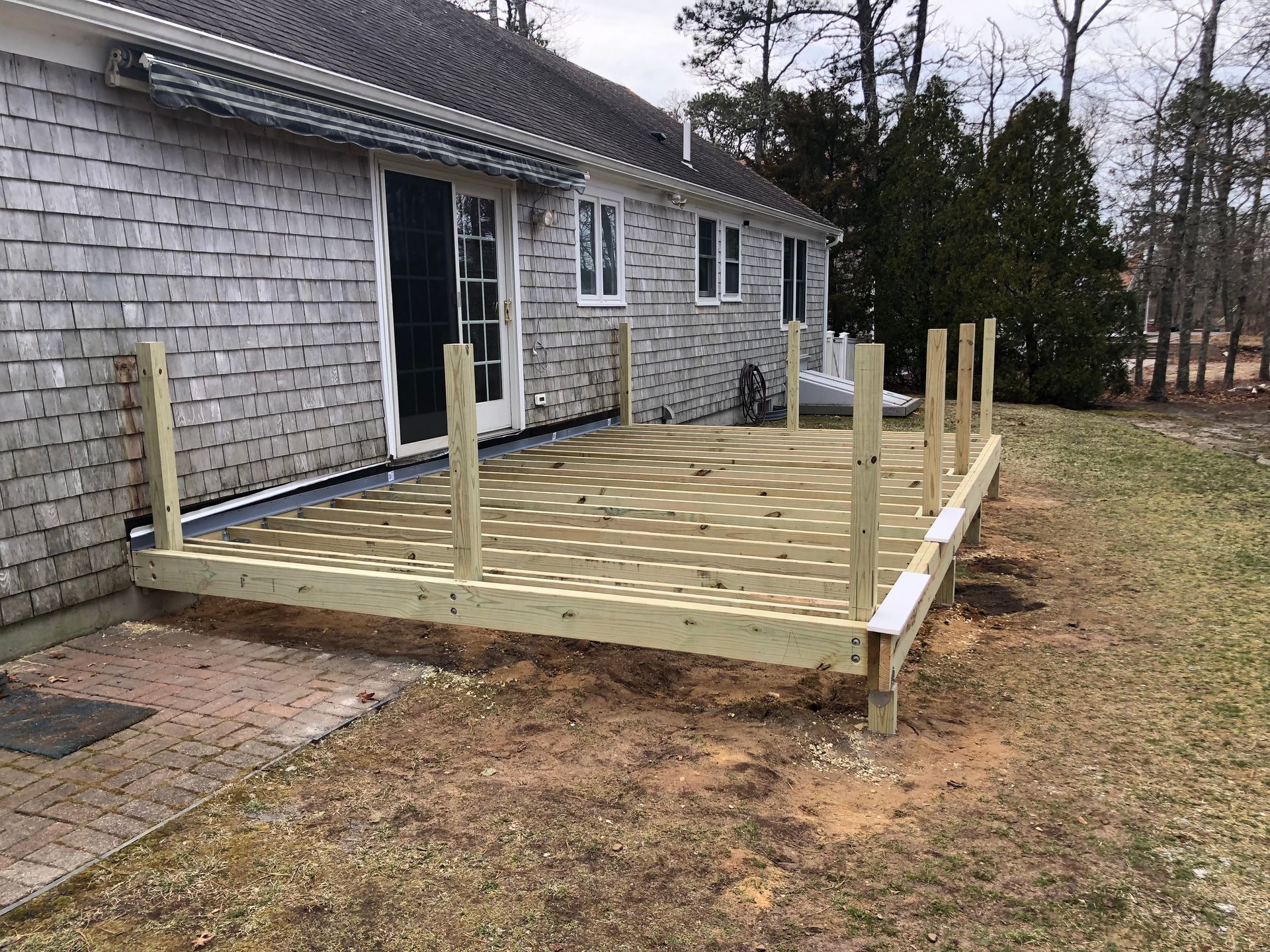 Newly constructed wooden deck attached to a gray-shingled house.
