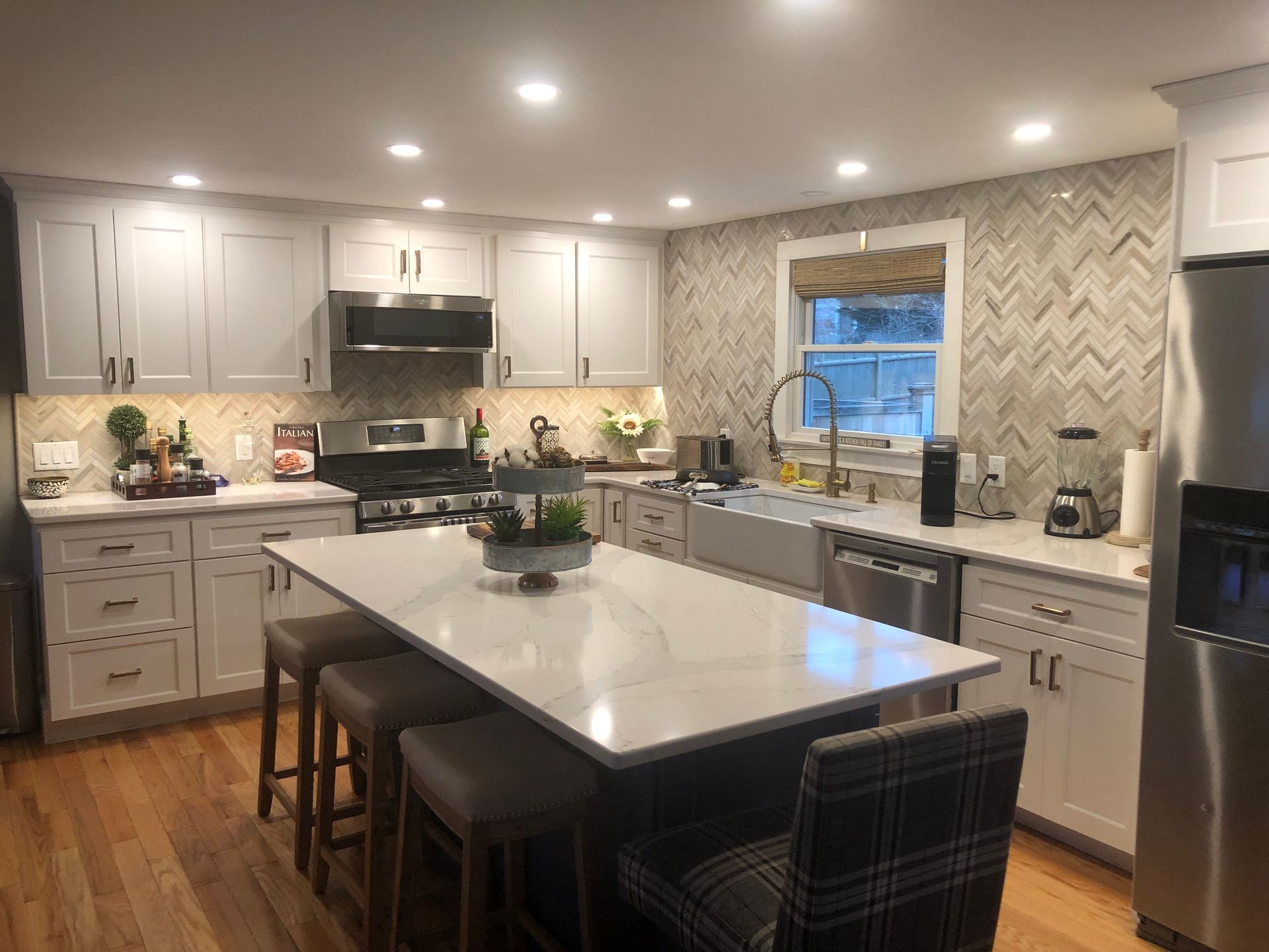 Modern kitchen with white cabinets, island, and stainless steel appliances.
