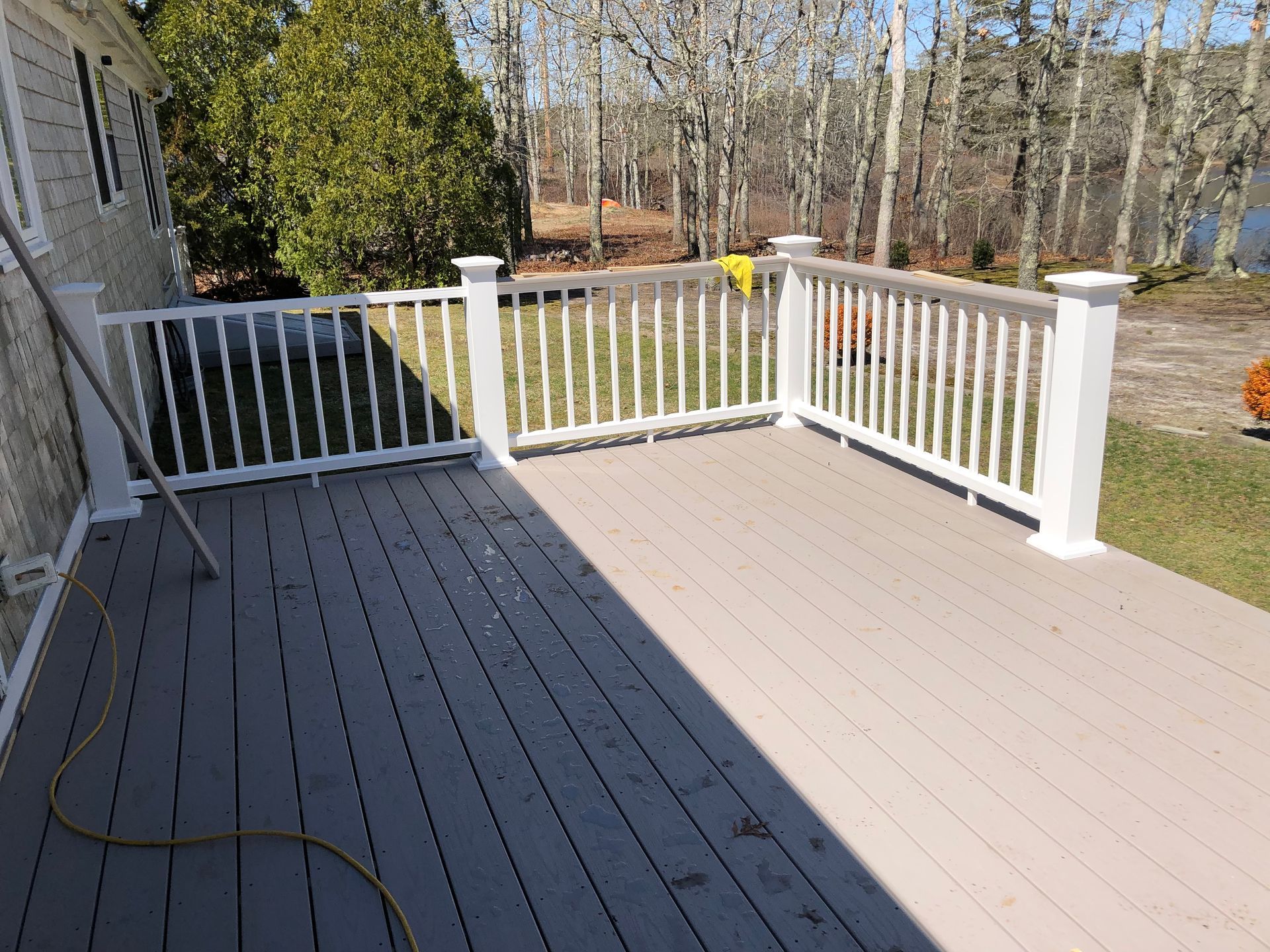 Deck with white railing and gray composite decking, overlooking a wooded area.