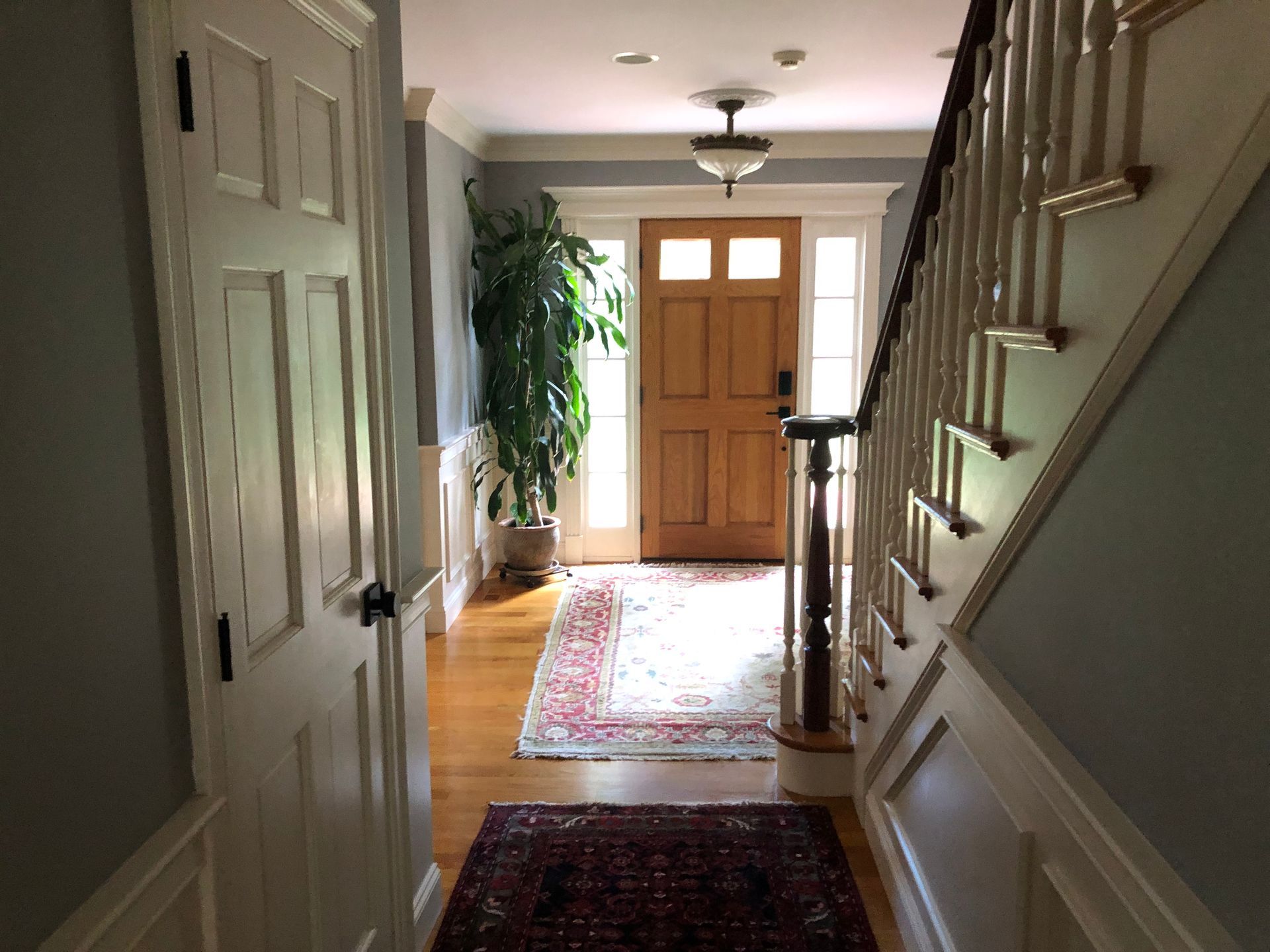Entryway with hardwood floors, wooden door, staircase, and oriental rugs.