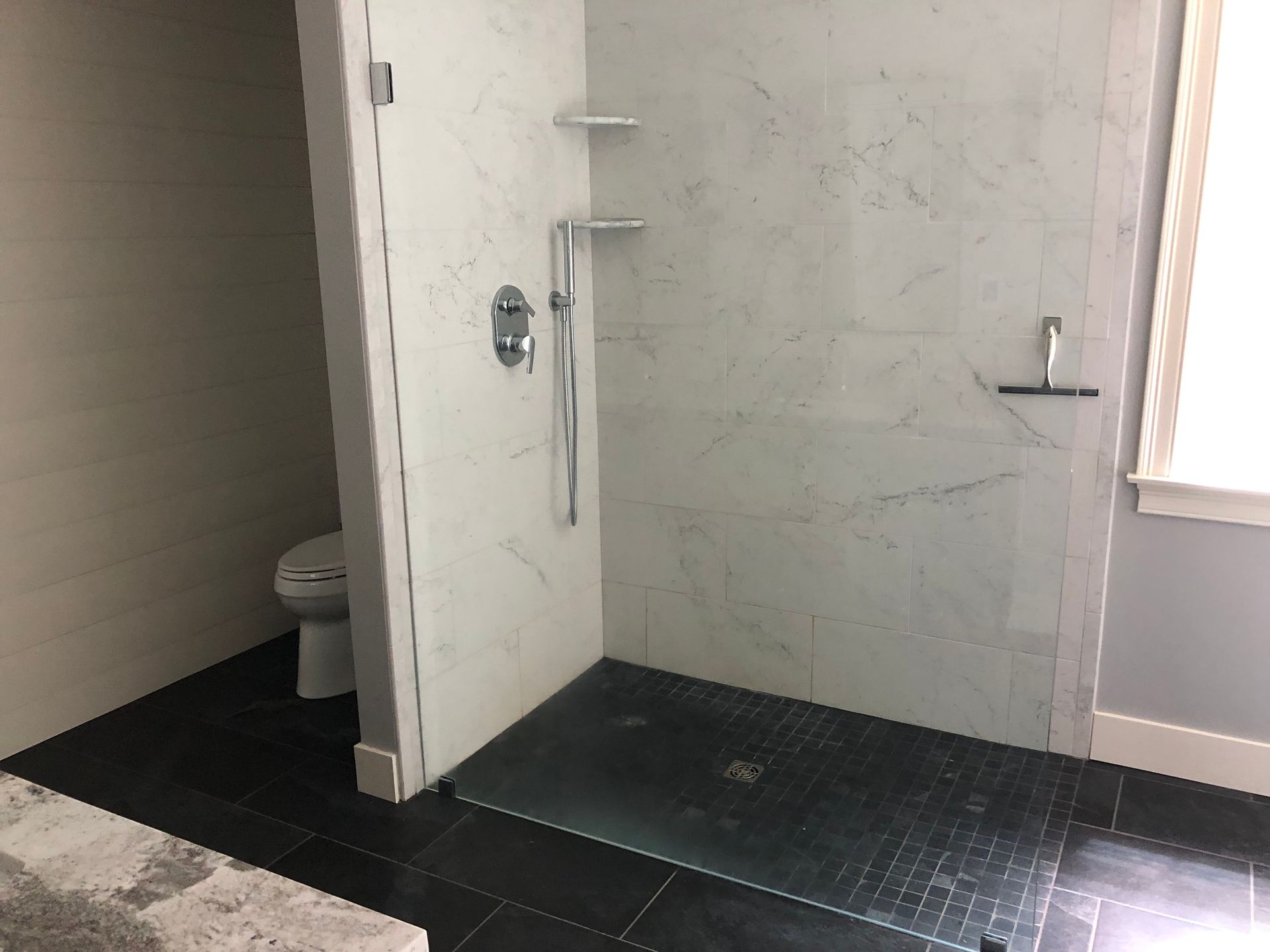 Bathroom with a tiled shower stall and a toilet.
