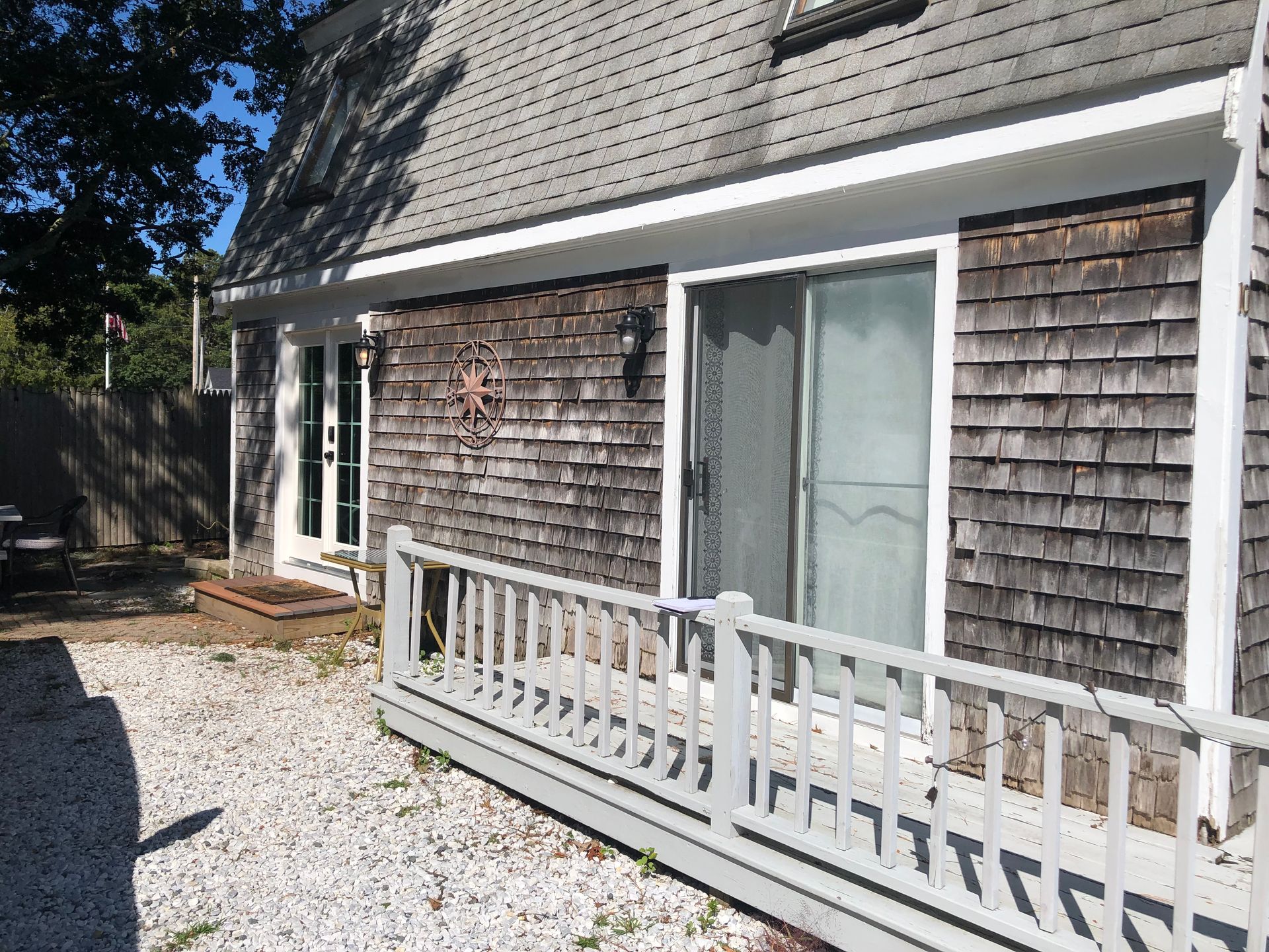 House exterior with weathered cedar shingles, deck, and sliding glass door.