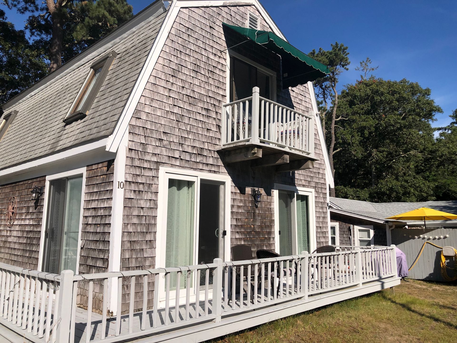 Wooden house with a balcony and an awning, blue sky in the background.