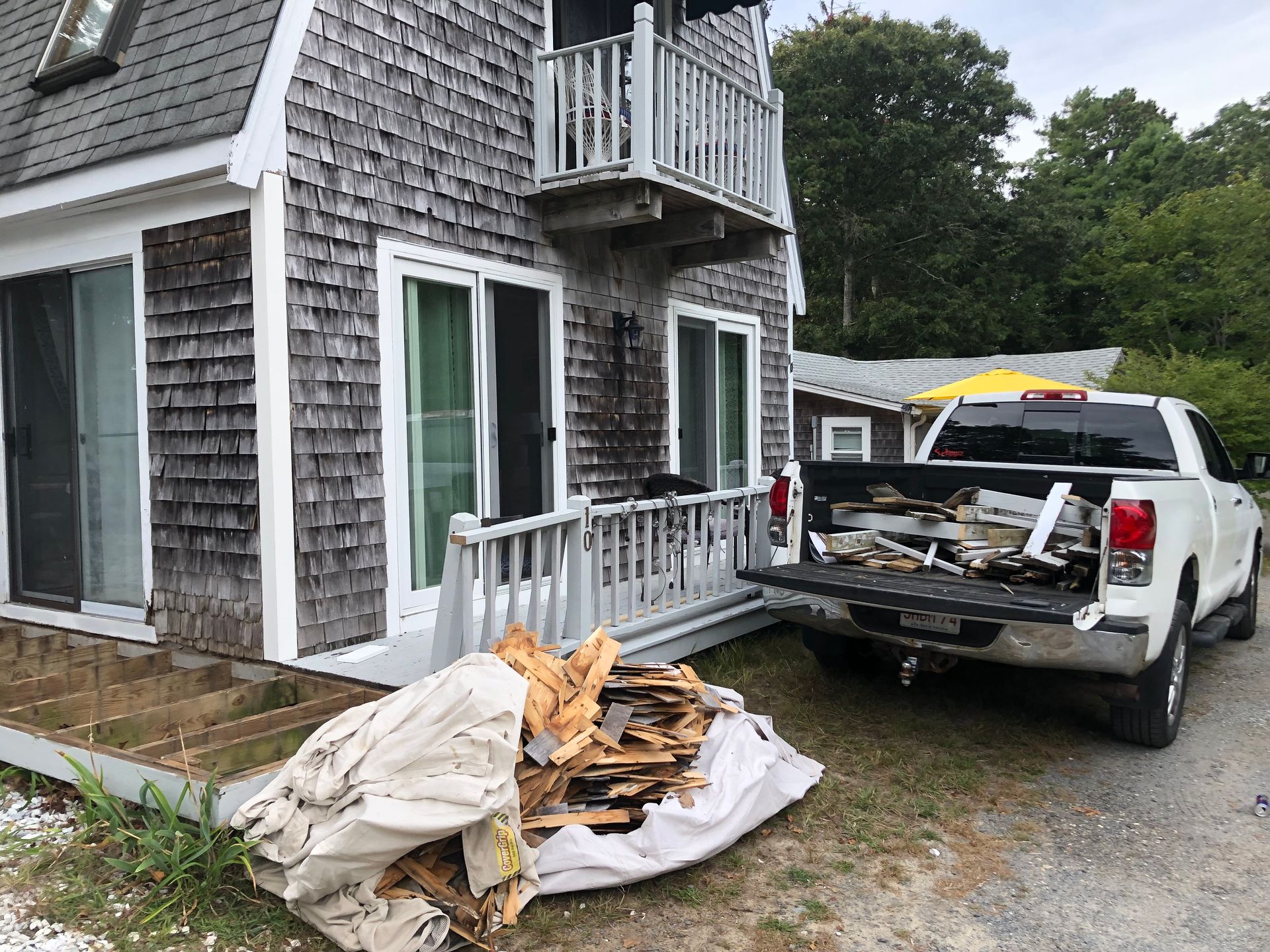 A white pickup truck with debris parked beside a house being renovated.