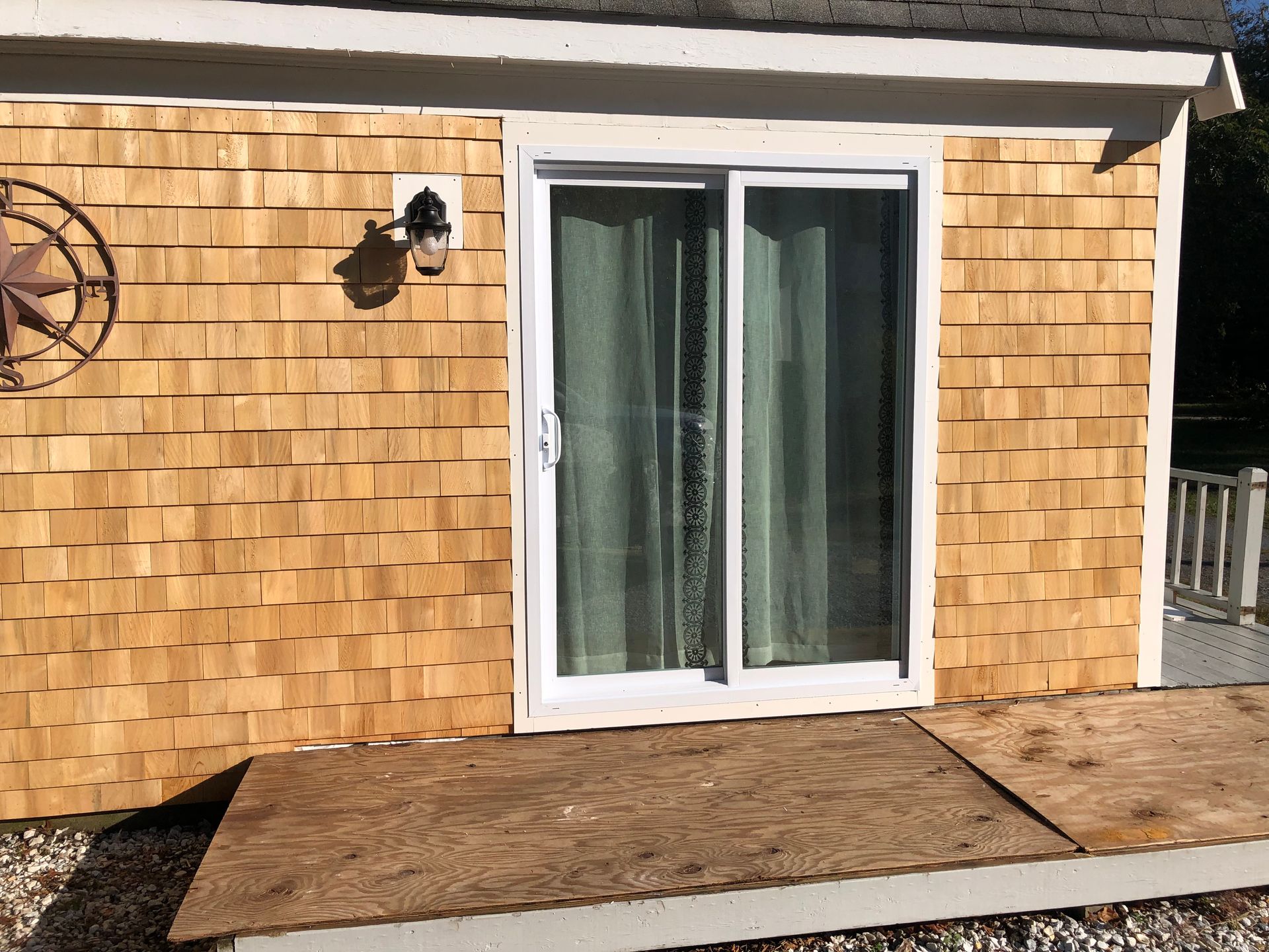 Exterior of a building with cedar shingle siding, a sliding glass door, and a wooden deck.