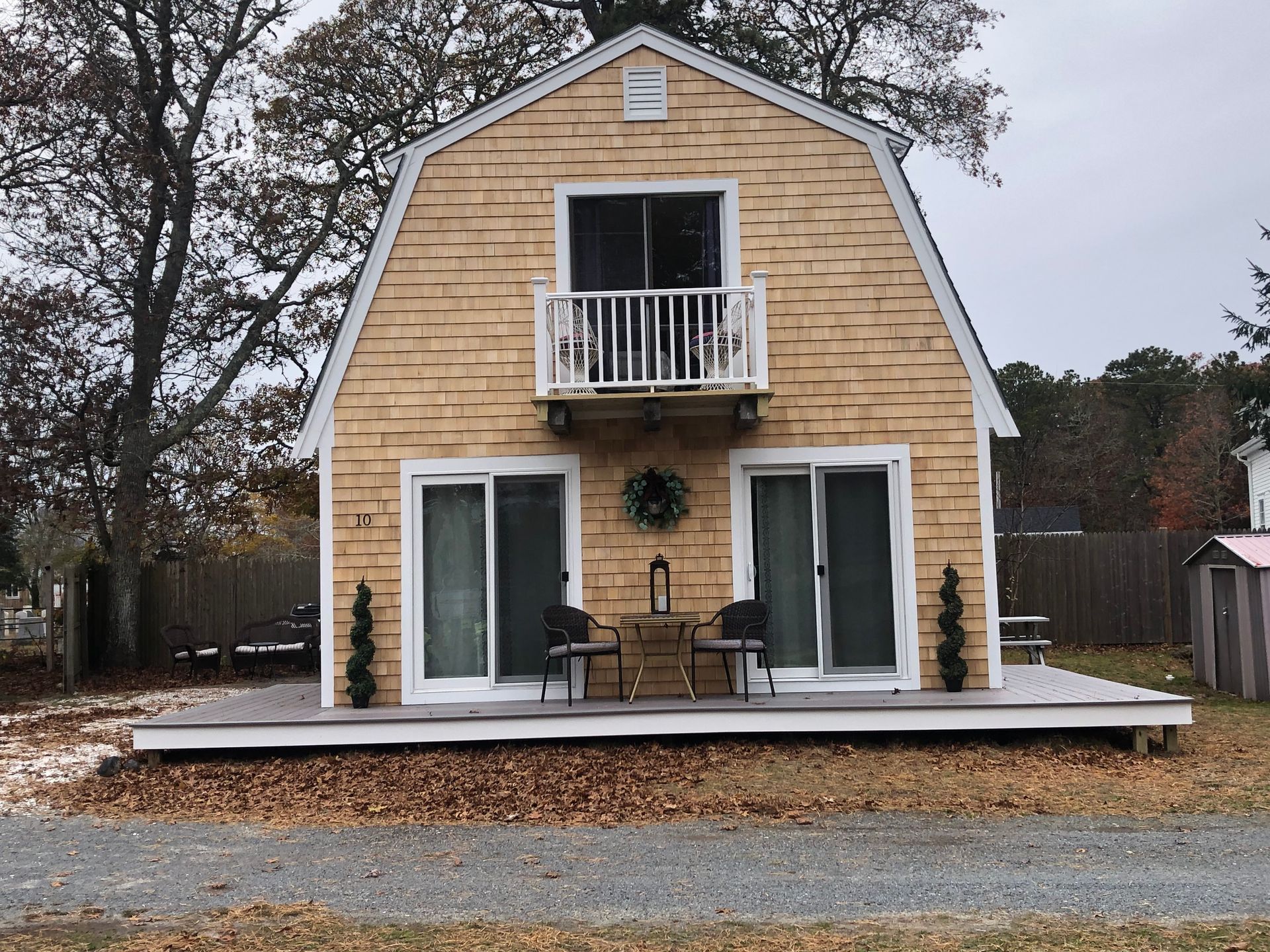 Barn-style house with cedar shingle siding and a small deck with sliding glass doors and a balcony.
