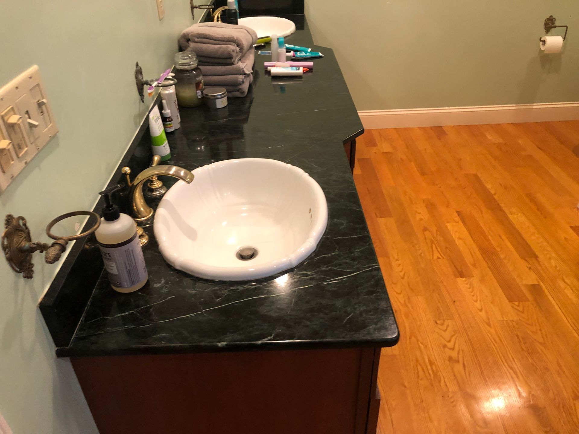 Bathroom vanity with a dark countertop and a white sink. Hardwood floor.