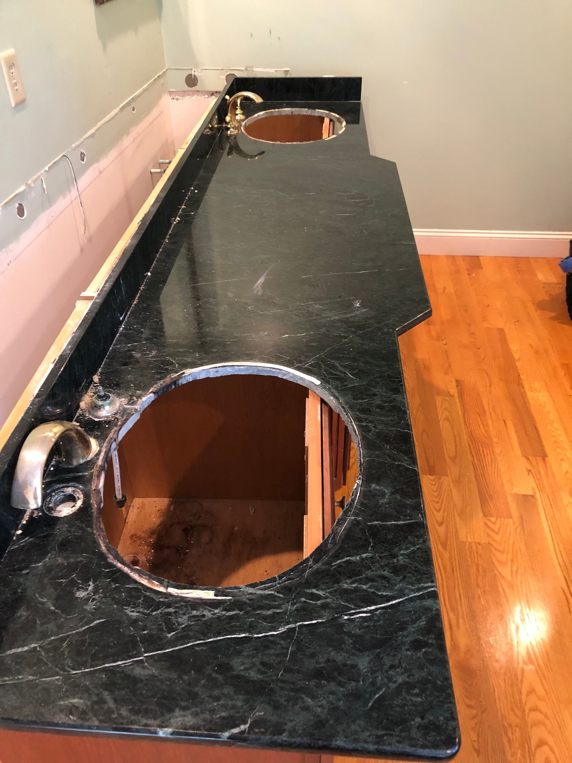 Dark green marble bathroom countertop with two sink cutouts, partially installed.