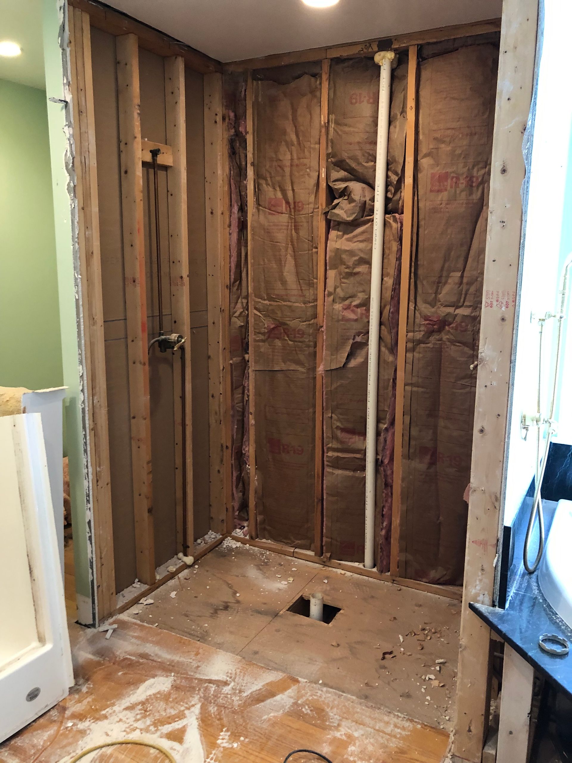 Bathroom renovation: shower stall framed with exposed studs, insulation, and plumbing.