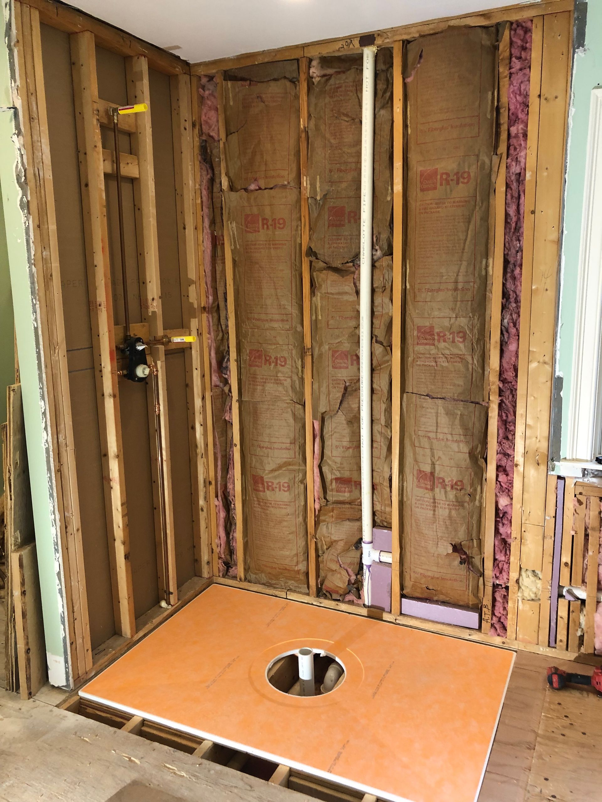 Framed shower stall under construction with orange tile base and insulation.