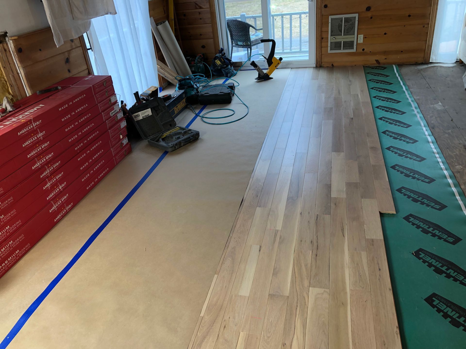Wooden flooring installation in progress; wood planks, tools, and underlayment visible.