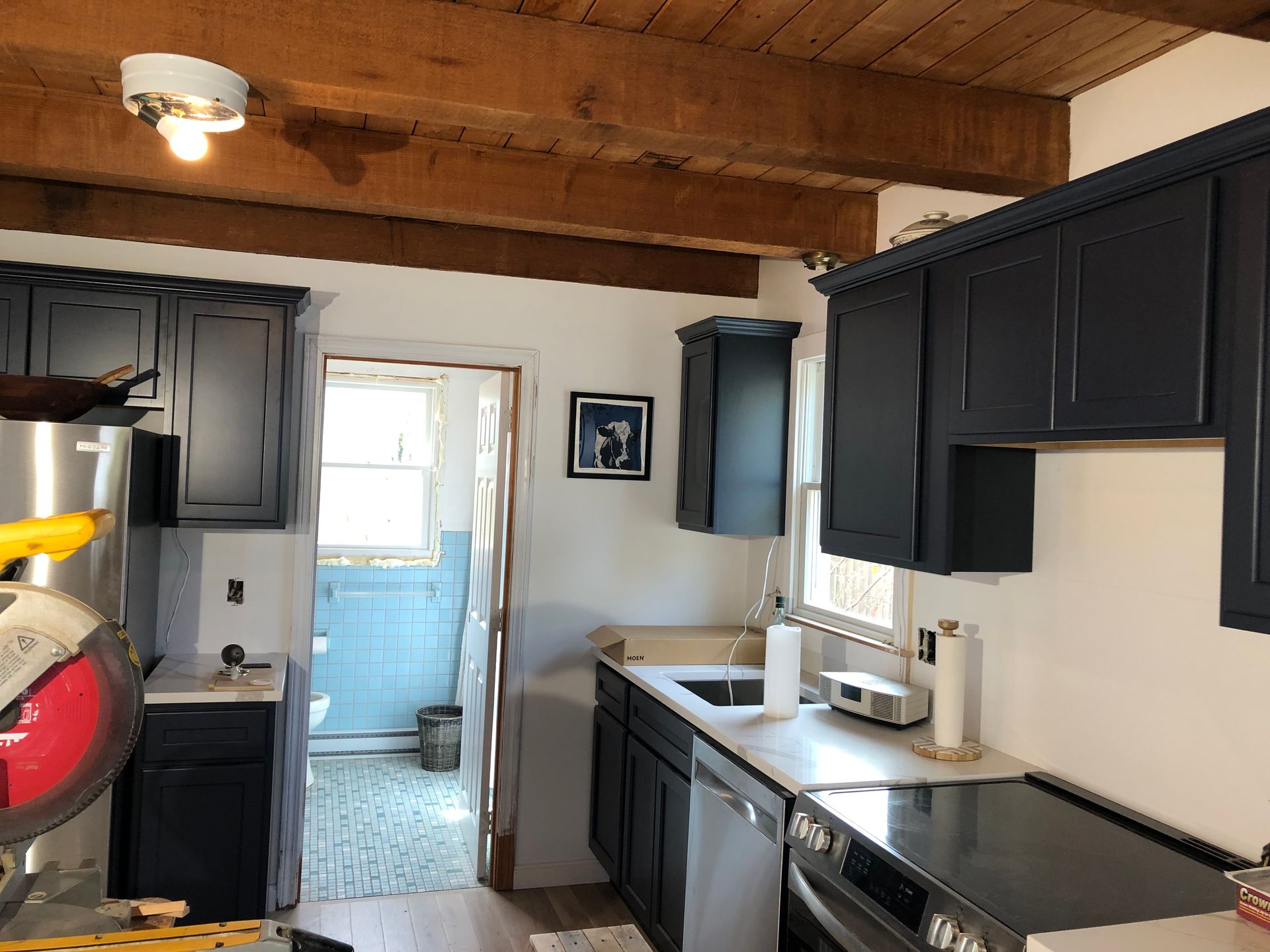Kitchen with dark blue cabinets, light countertops, and exposed wooden beams.