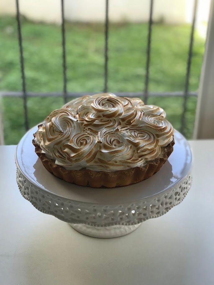Tarta de merengue de limón sobre base de tarta blanca, con fondo verde difuminado.