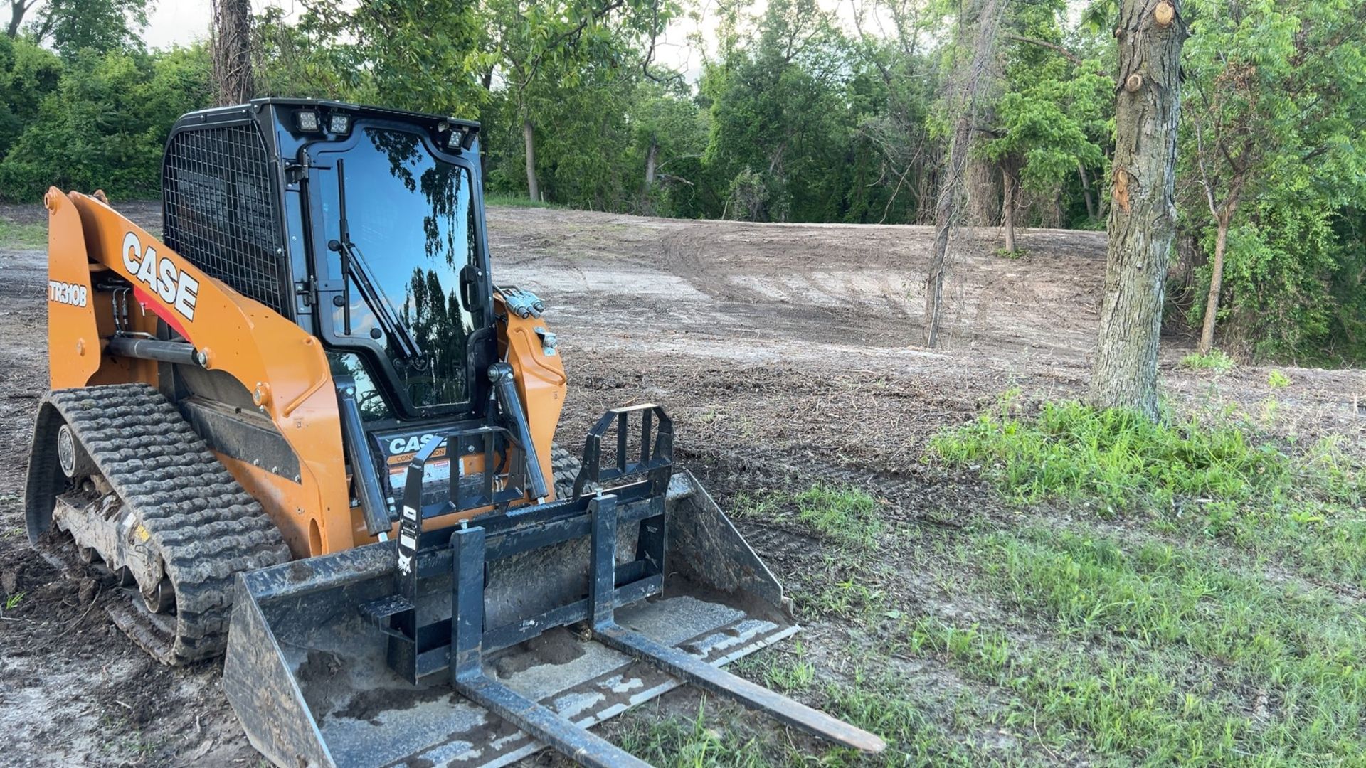 A lush green hillside with lots of mulch and plants in front of a house.