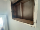 Recessed wooden shelf in a light blue wall, painted white trim, interior space.