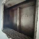 Rectangular opening in a concrete wall, with a central support. Debris at the bottom, dark interior.