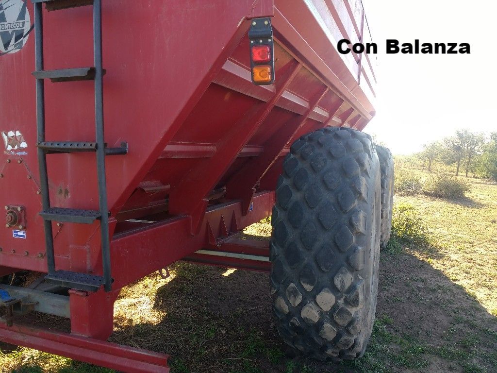 Carro de grano rojo con neumáticos grandes, escalera y luces en un campo.