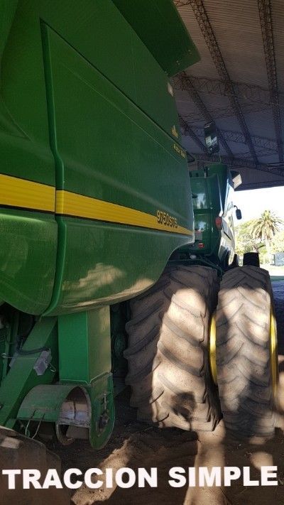 Tractor John Deere verde estacionado dentro de una estructura, texto "TRACCION SIMPLE" en la parte inferior.