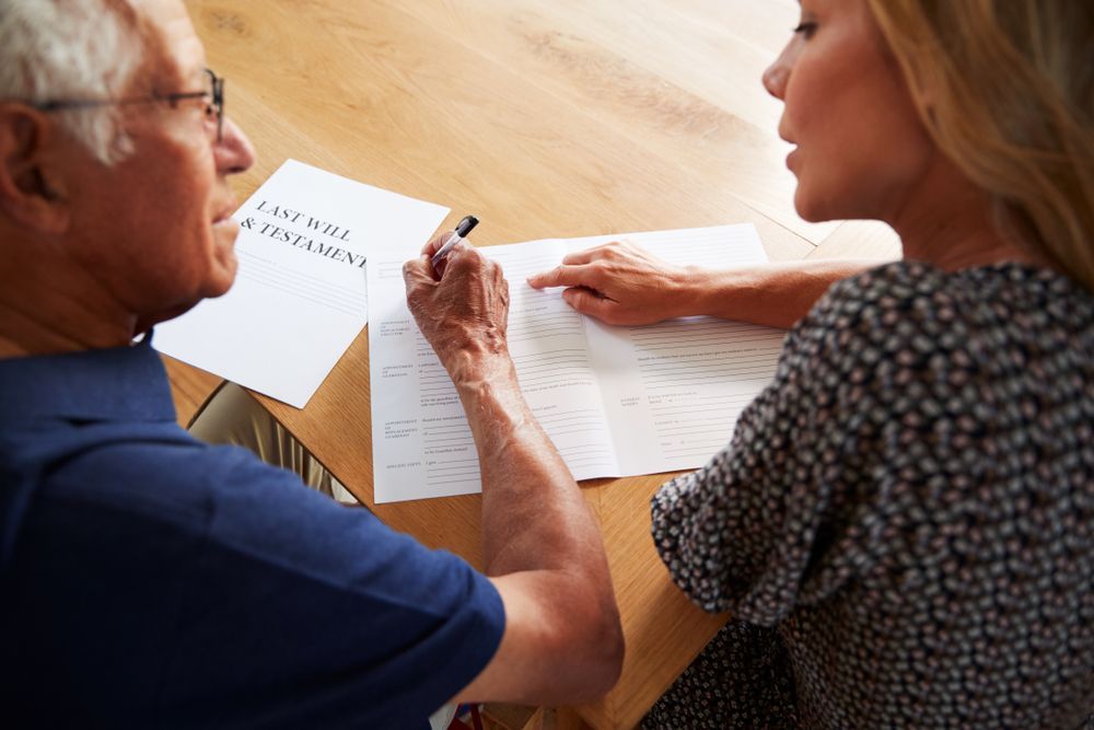 A Man and a Woman Are Sitting at a Table Signing a Document — Hynes & McCormack In Murwillumbah, NSW