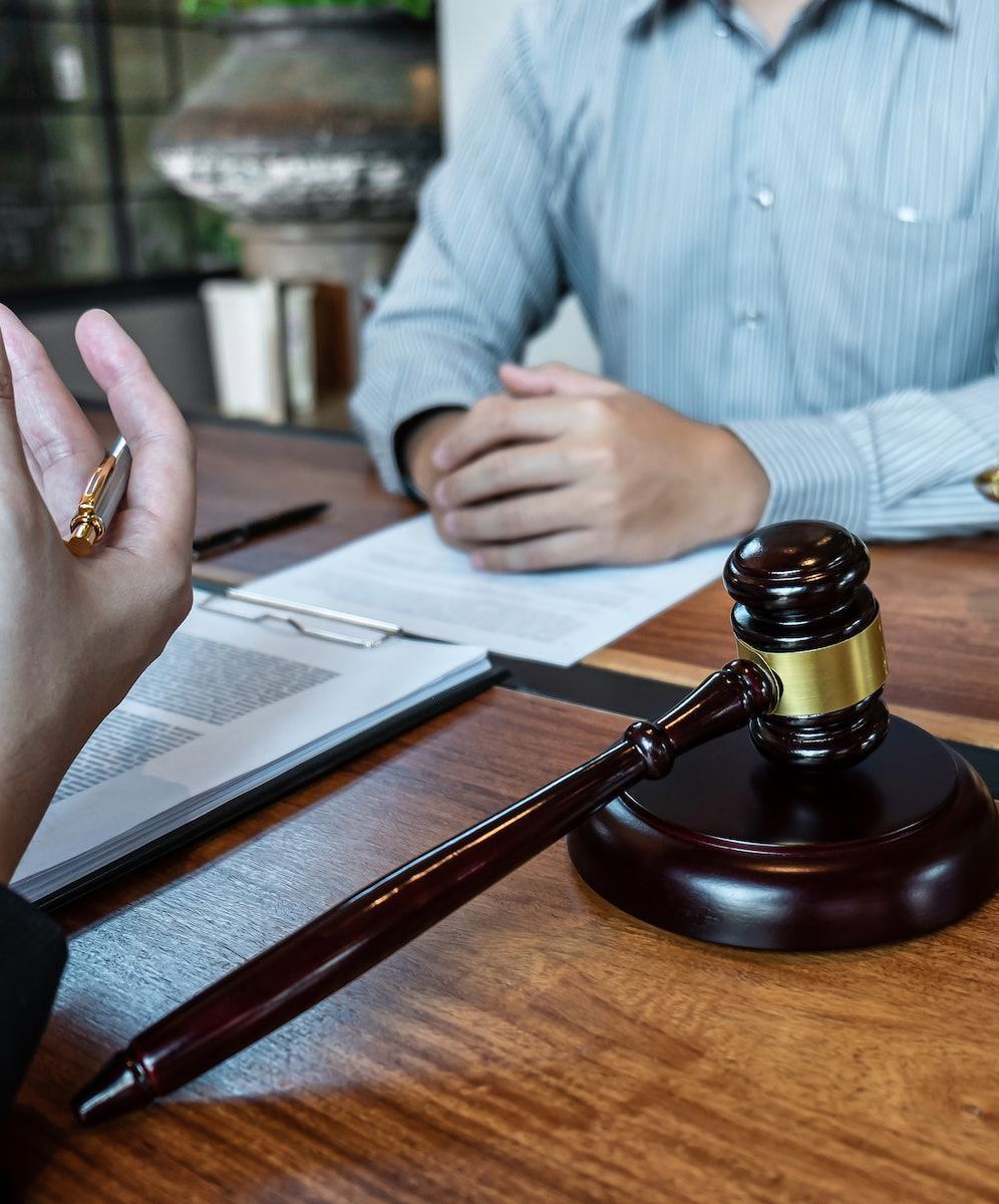 A Man is Sitting at a Table With a Judge's Gavel and Scales of Justice — Hynes & McCormack In Murwillumbah, NSW