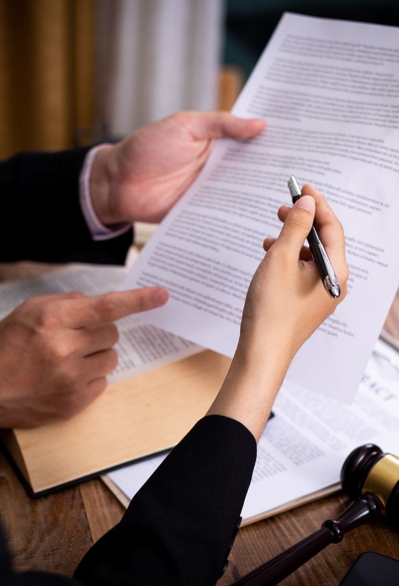 A Man and a Woman Are Sitting at a Table Looking at a Piece of Paper — Hynes & McCormack In Murwillumbah, NSW