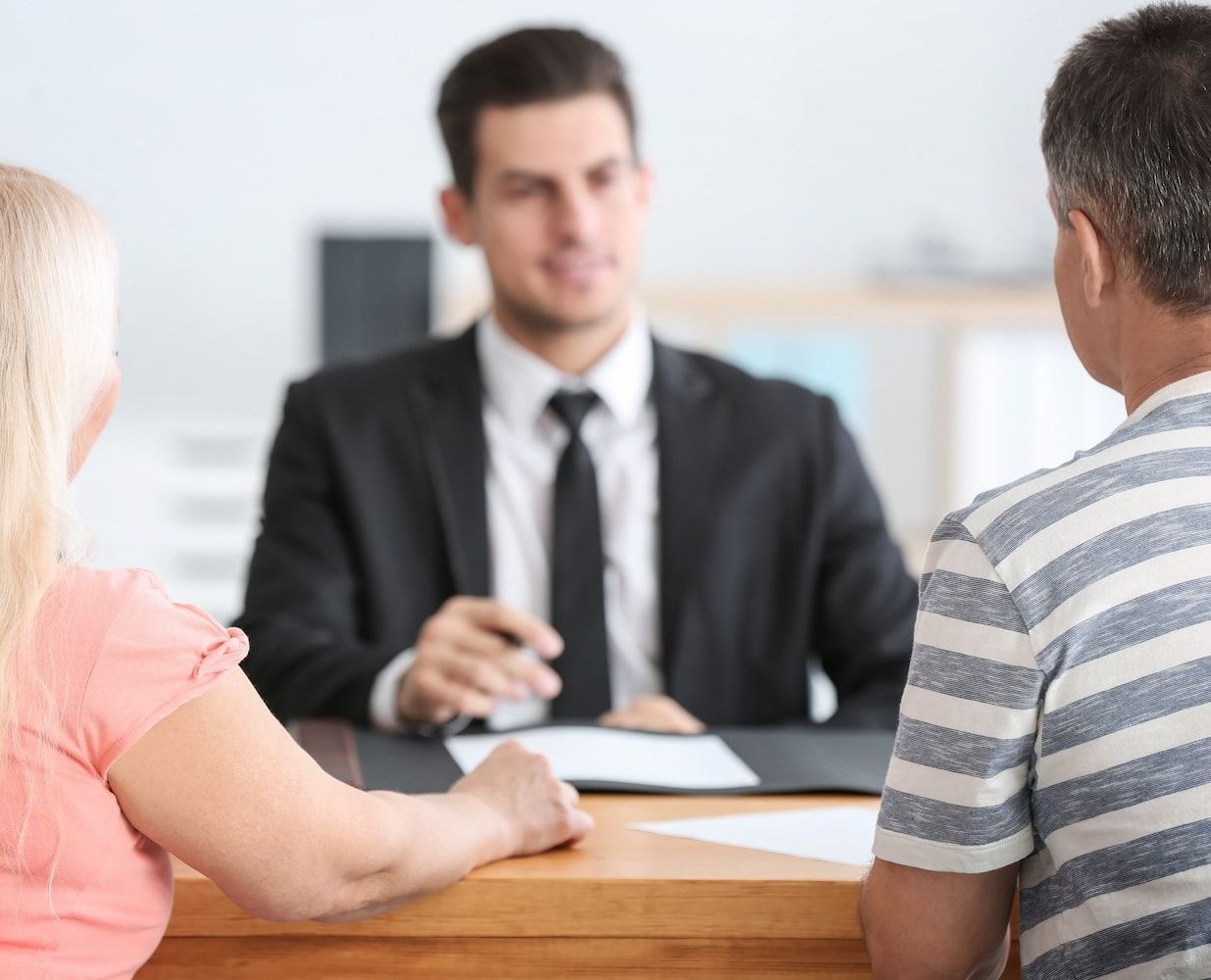 A Man and a Woman Are Sitting at a Table Talking to a Man in a Suit and Tie — Hynes & McCormack In Murwillumbah, NSW