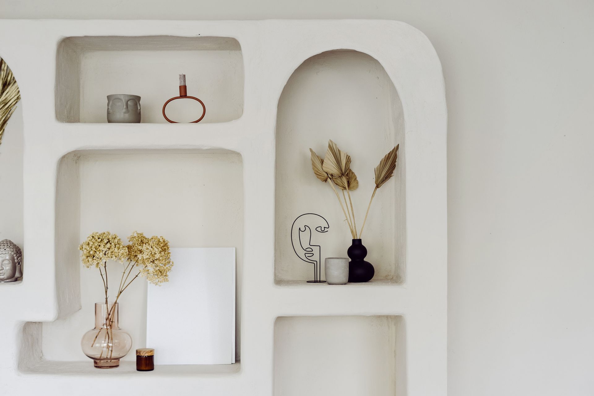 A white shelf with a vase of flowers and candles on it.