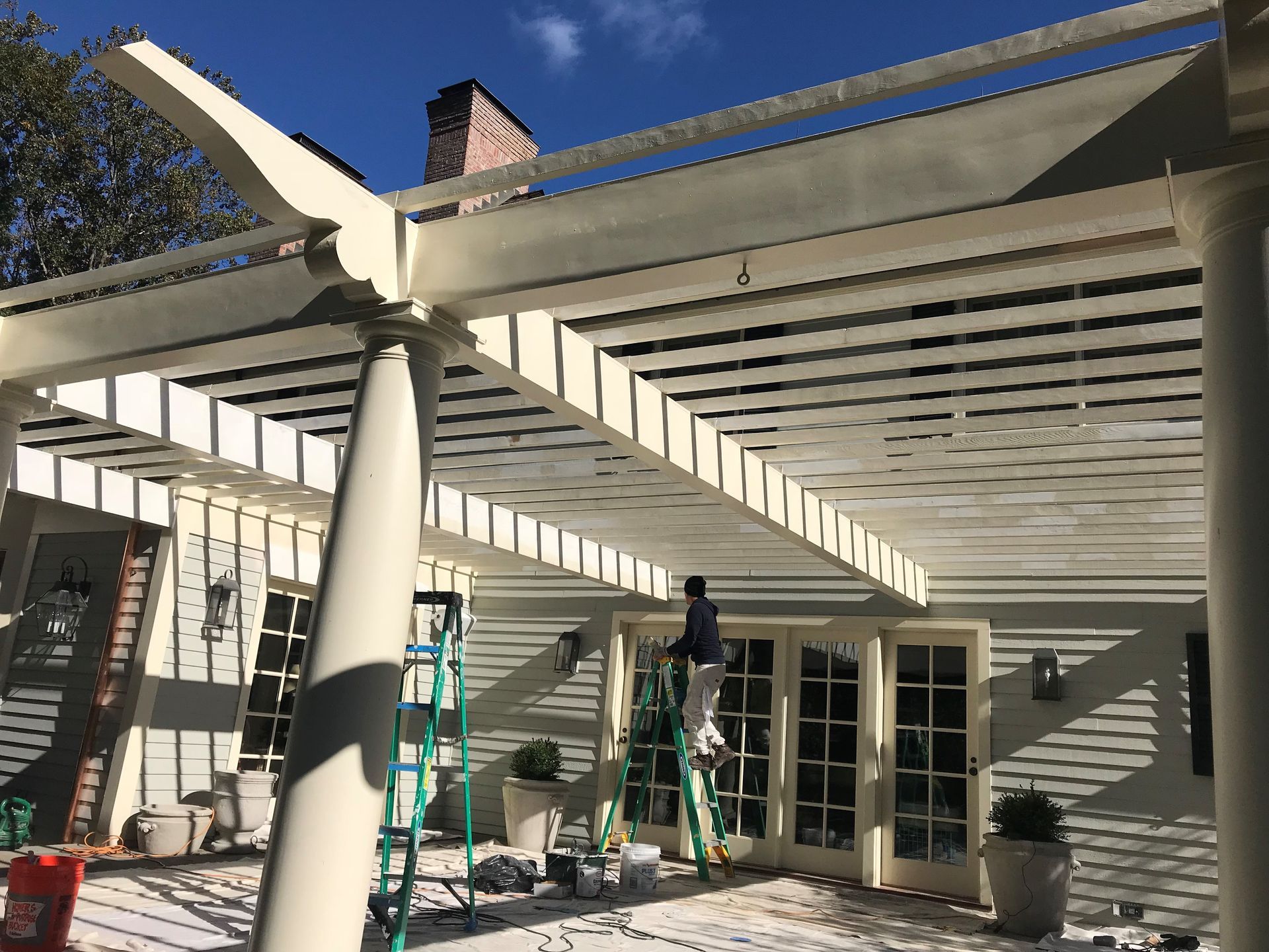 A person is painting a wooden deck with a mop.