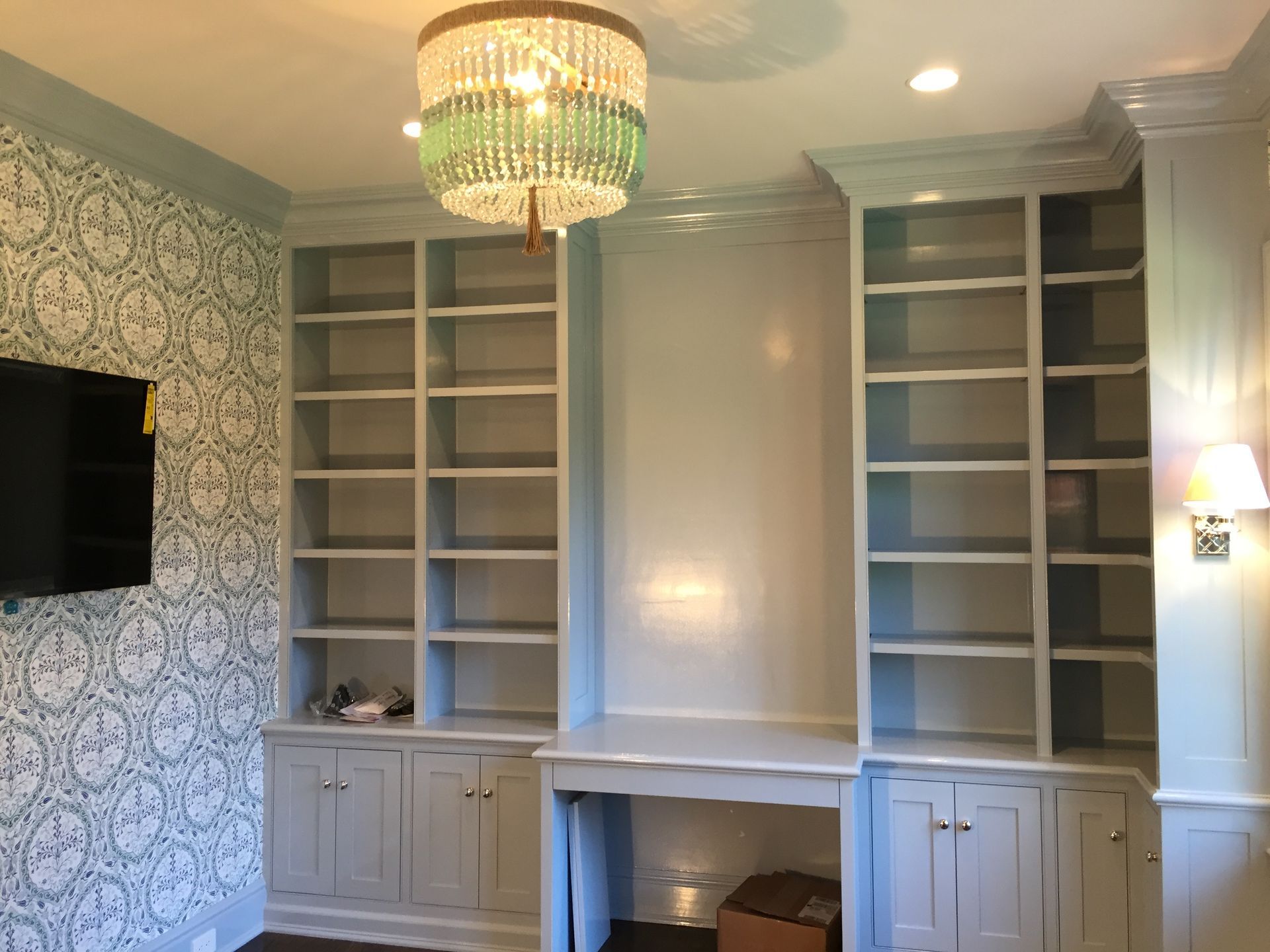 A man is painting a wall in a room next to a ladder.