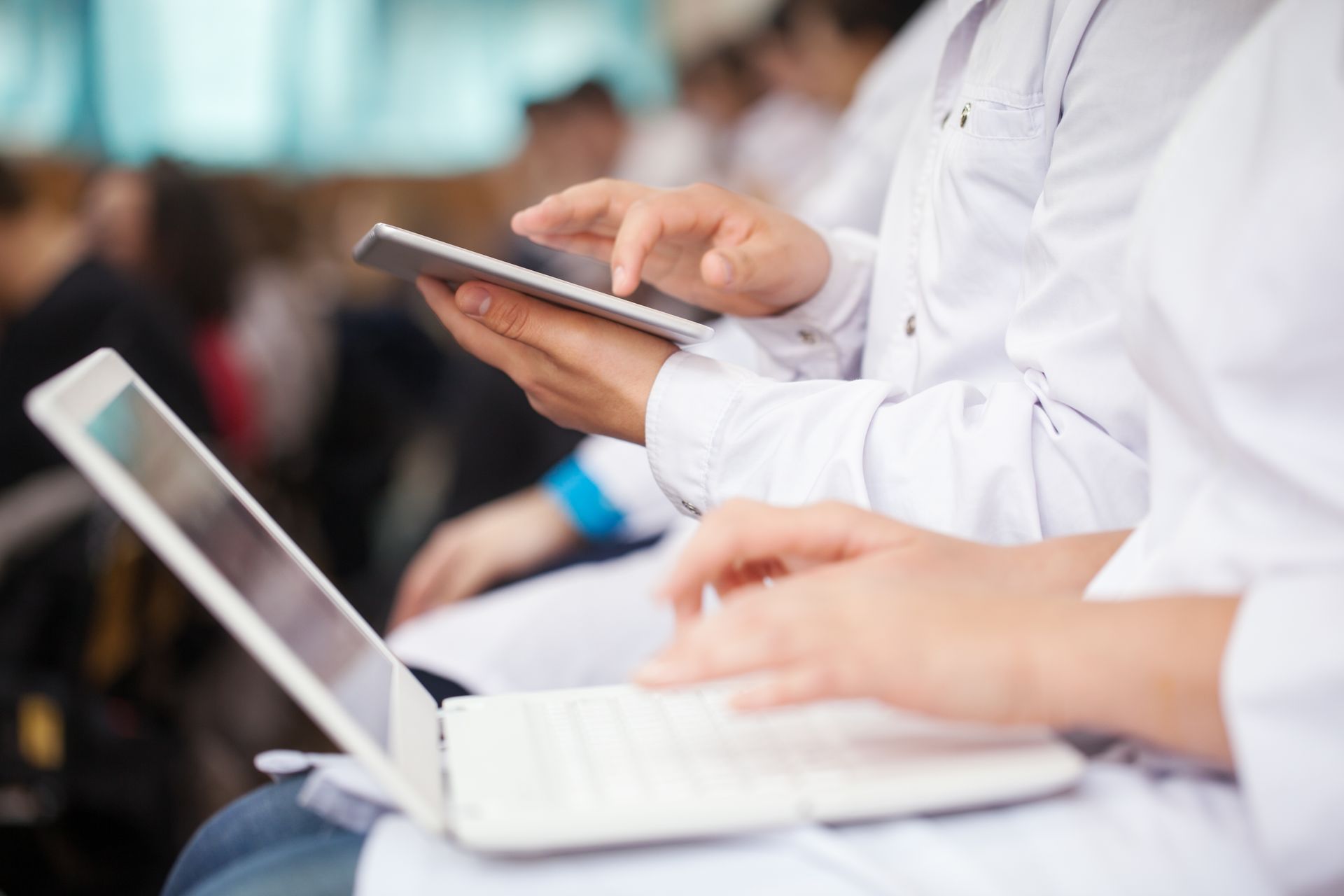 un gruppo di medici è seduto in fila utilizzando laptop e tablet.