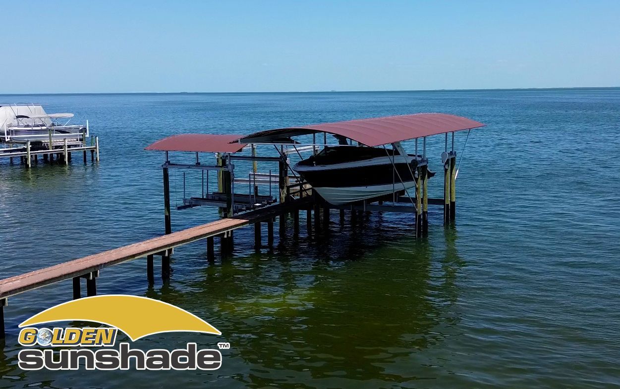 A boat is docked at a dock with a sunshade over it.