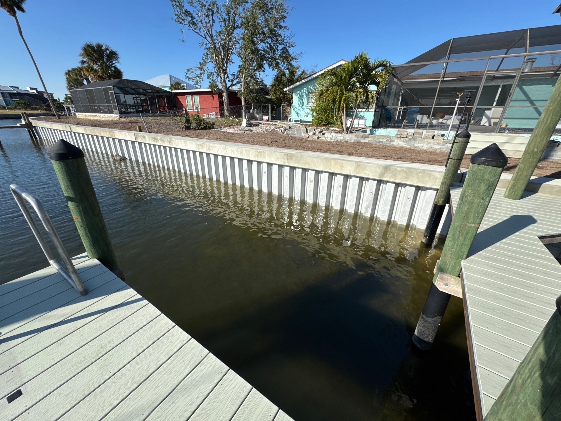 A concrete wall surrounds a body of water with a dock in the background.