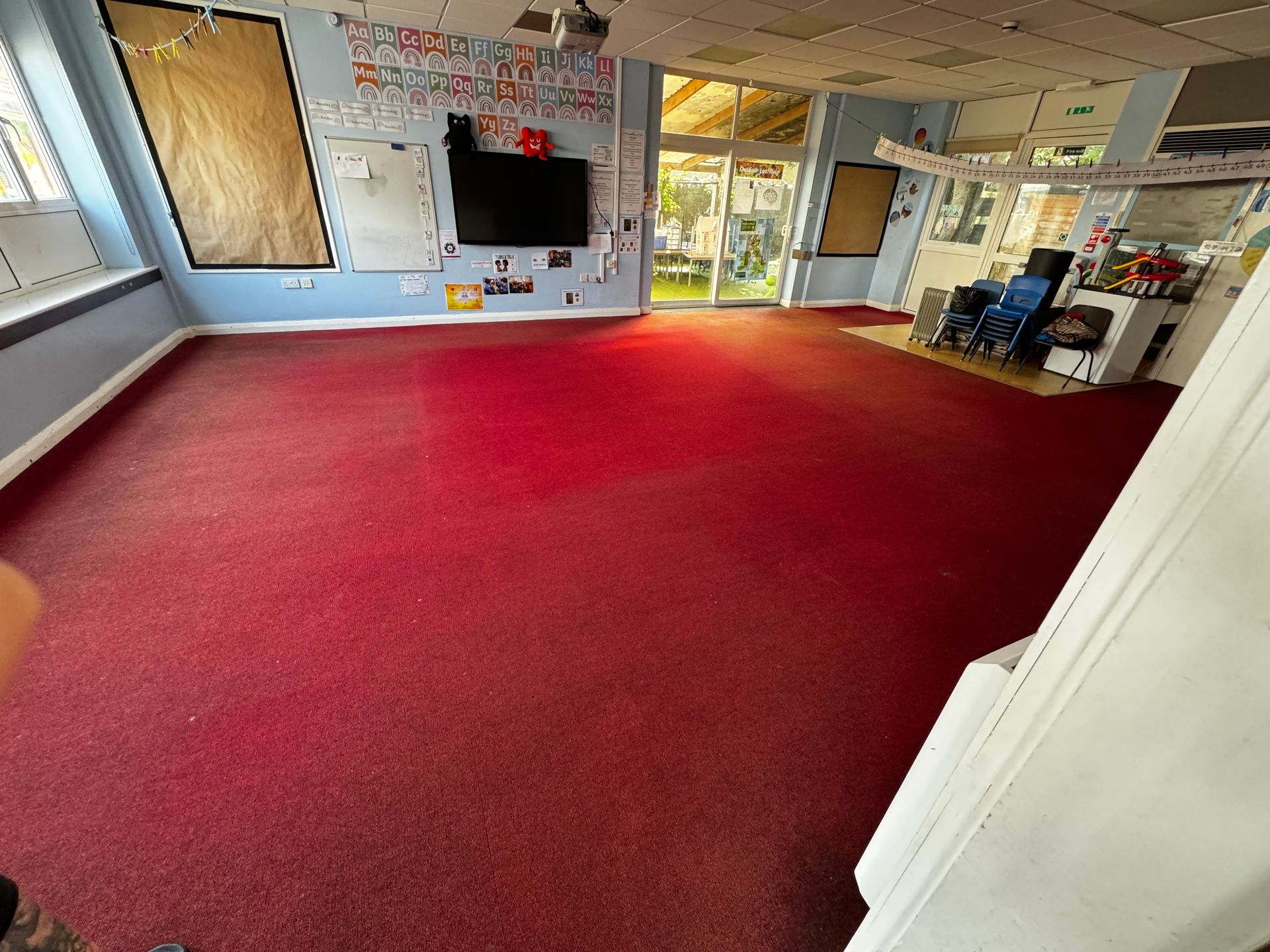 A large room with a red carpet and a flat screen tv on the wall.