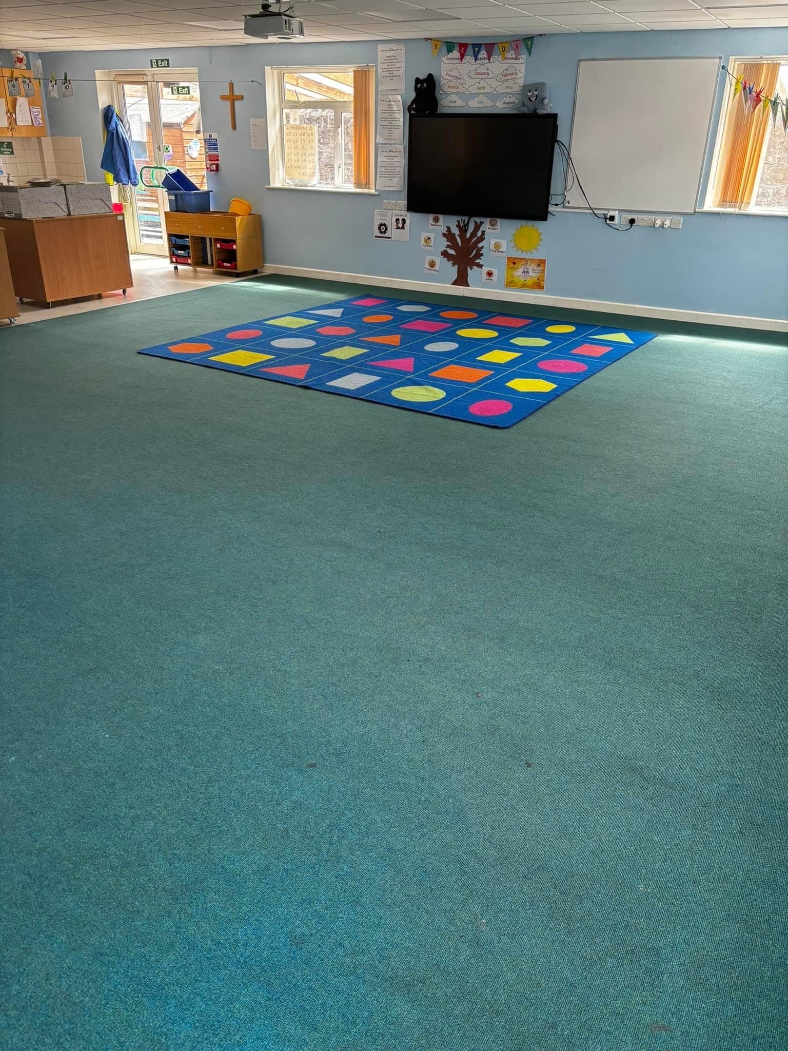 A classroom with a blue carpet and a twister mat on the floor.