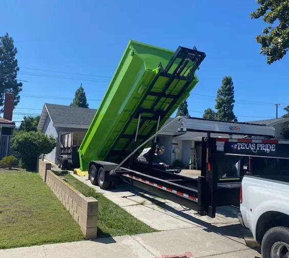 A green dump truck is parked in front of a house