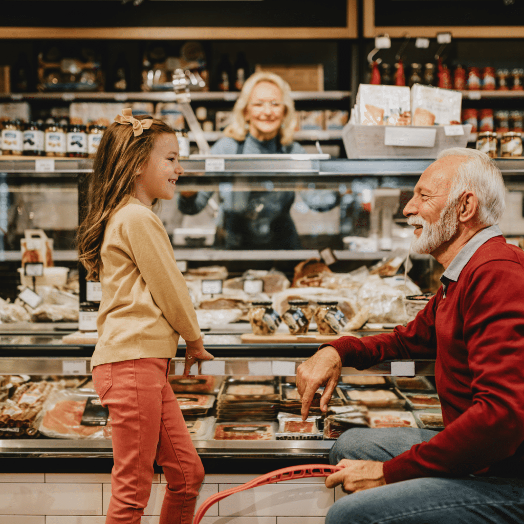 A man and a little girl are standing in front of a display case in a bakery.