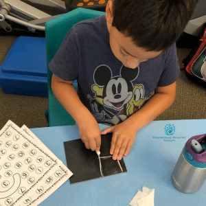 A young boy wearing a mickey mouse shirt sits at a table