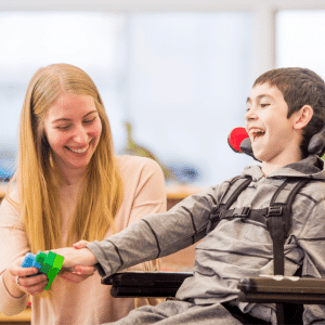 A woman is playing with a child in a wheelchair.