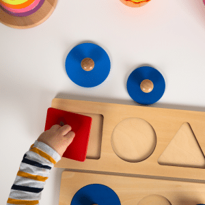 A child is playing with a wooden puzzle with circles and triangles