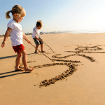 A boy and a girl are playing in the sand on the beach.